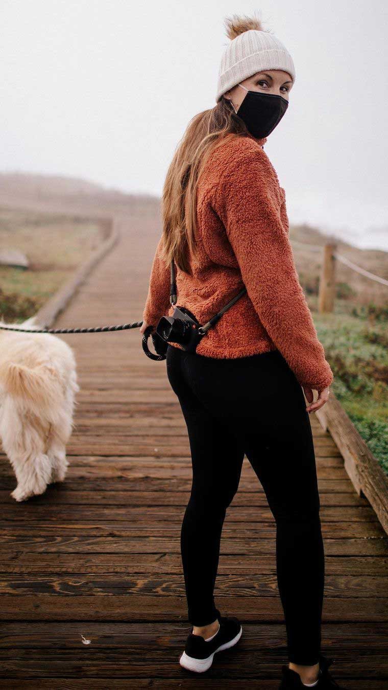 An influencer who partnered with Visit Cambria walking her dog on a leash on a Cambria boardwalk