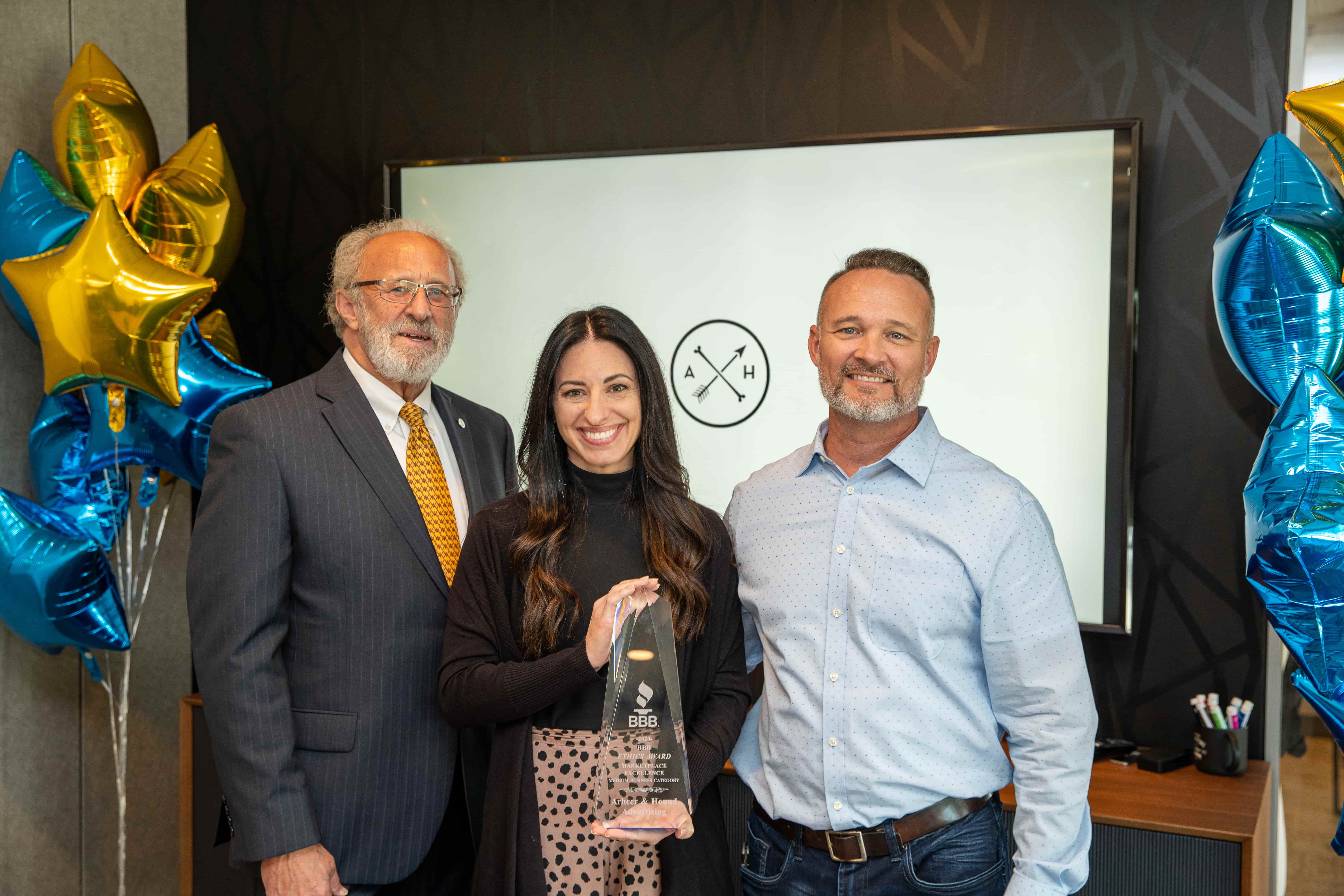 Archer & Hound co-owners Jessica Blanchfield and David Blanchfield smiling at the camera with Better Business Bureau President and CEO Blair Looney during a presentation of Archer & Hound's Ethics Award in 2021